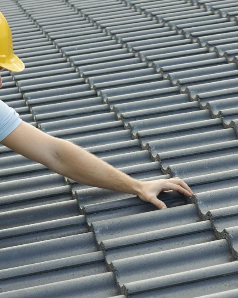 A man wearing a hard hat and yellow safety vest on a roof, showcasing our roofing services in San Francisco, CA.